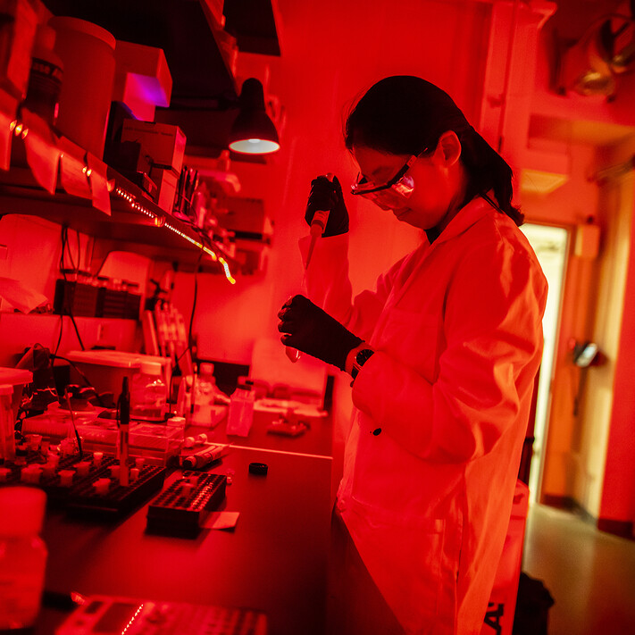 lab technician using pipette in red light