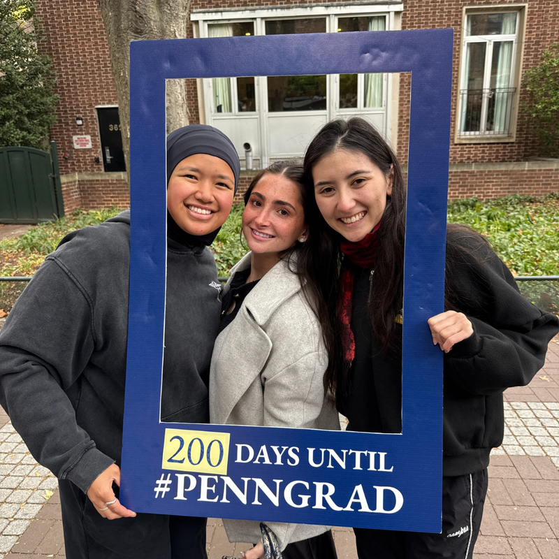 3 students holding a frame and posing with a sign that reads "200 Days Until #PennGrad"